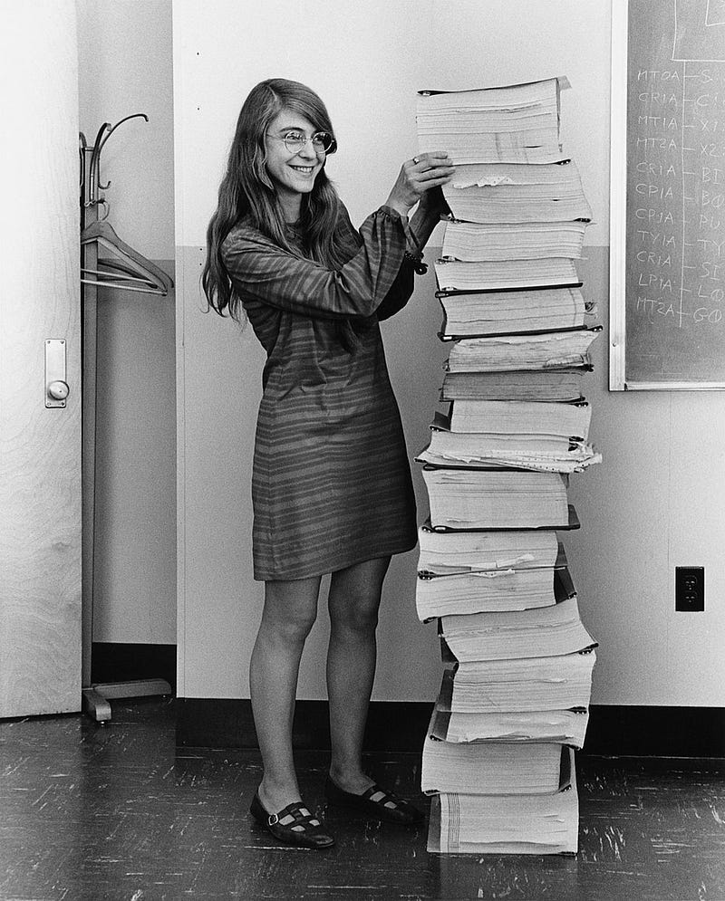 Margaret Hamilton alongside her Apollo project software listings